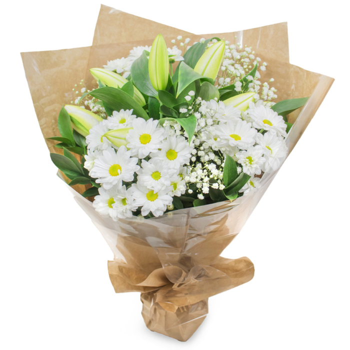 Presented upright against a pristine white background, this elegant hand-tied bouquet balances white and green in a composition that feels both timeless and softly optimistic. The arrangement centers on numerous white chrysanthemum heads, their concentric layers of slender petals unfurling from bright yellow centers to create a joyful, classic presence. Mixed through these are several pale green-yellow lily buds, their long, graceful forms still closed and suggesting a quiet narrative of growth; faint striping along some buds hints at the fuller lilies to come, adding a refined sense of anticipation. Intermittent sprays of gypsophila (baby's breath) add a delicate, cloud-like texture-tiny white blossoms that puff around the larger flowers and catch the eye with their airy lightness. Deep green foliage provides a vibrant contrast, framing the whites and lending visual weight and depth. The bouquet is wrapped in two thoughtful layers: an inner sheet of rustic, crinkled brown kraft paper that offers warmth and an artisan touch, and an outer cellophane wrap that is clear and glossy, protecting the stems while letting the whole bouquet shine under soft light. The base is neatly gathered and secured to form a neat, portable bundle. The aroma is subtle-clean green notes with a faint sweetness-making this composition appropriate for celebrations as well as sympathetic gestures. It echoes the calm confidence of a local florist's selection, suited to delivery across Nine Elms, along Nine Elms Lane, or to a quiet apartment near Battersea Park where simple, elegant flowers say what words sometimes cannot.