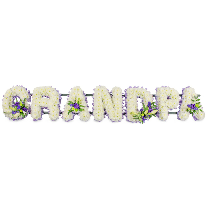 A serene sympathy arrangement in the shape of the word GRANDPA stretches horizontally across the frame, each capital letter built on a hidden structure and presented against a clean, white studio-style background. The florist has covered every surface of the letters with massed white flowers-most likely small chrysanthemums or carnations-arranged so densely that they form smooth, rounded contours. The white blooms appear freshly opened, their petals slightly ruffled, creating a soft, tactile surface that suggests comfort, gentleness, and peace. Here and there, clusters of rich purple and lavender flowers break through the field of white, accompanied by small leaves of deep green foliage. These coloured details sit in the inner curve of the G, nestle in the triangle-shaped gaps of both As, anchor the middle of the D, and accent the bowl and stem of the P, bringing a measured touch of contrast and visual depth. Beneath the letters, a dark green bar or rail, mostly obscured by petals, supports the design and keeps the tribute level, making it suitable for resting on trestles at a funeral service or along the front of a hearse travelling through Nine Elms towards Vauxhall or along the river. Crafted by a skilled florist, the piece feels both strong and tender, a personalised farewell that speaks directly of a grandfather's role at the heart of the family. In its simplicity of white, purple, and green, the arrangement quietly expresses gratitude, remembrance, and a final, dignified goodbye.