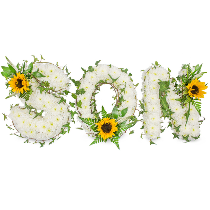 A detailed, sculpted funeral tribute photographed against a clean white studio background, meticulously spelling out SON in three bold, capital letters formed from a dense carpet of small white chrysanthemums. The chrysanthemums create a tactile surface that reads soft and cloudlike, each bloom placed to maintain crisp letter definition while allowing depth of shadow between clusters. Integrated into the white floral field are stems of dark green ivy, their trailing vines threaded through the letters to add natural rhythm and an evergreen contrast. Lighter green fern fronds and assorted pointed leaves are woven particularly around the O, where they fan beneath a prominent sunflower positioned low on the curve; this sunflower's broad yellow rays and dark-brown centre introduce warmth and visual balance. Another sunflower anchors the upper-left curve of the S, while the third crowns the upper-right of the N, their placement guiding the viewer's gaze left to right across the tribute. The arrangement balances solemnity and brightness: white blooms speak of peace, greenery of life's continuity, and sunflowers of remembrance and affection. The photograph's high-key white background makes the textures and colours read with clarity, useful for families and funeral directors in Nine Elms, Vauxhall, and nearby Kennington assessing the piece's craftsmanship and scale. This bespoke memorial design reflects experienced floristry technique - compact flower placement, considered foliage integration, and purposeful colour accents - ideal for honouring a beloved son at a funeral or memorial service.