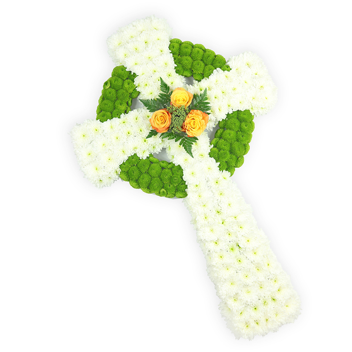 A meticulously arranged Celtic cross of fresh flowers, presented on a clean white surface and photographed from a slightly elevated view to show its full depth and contour. The cross is predominantly formed of small, tightly packed white spray chrysanthemums, their delicate, layered petals creating a soft, dignified texture that reads like a blanket of remembrance. Accenting that white canvas are bright, almost lime-green button chrysanthemums that have been used with deliberate rhythm: they trace the circular ring at the intersection of the arms and fill alternating segments along the horizontal arm, producing a plush, graphic contrast that suggests traditional Celtic knotwork in floral form. Anchoring the design at its centre is a compact trio of orange-yellow roses - richer towards a golden-orange - whose warm, velvety petals act as an intimate focal point and bring a quiet optimism to the arrangement. A few dark green fern sprigs cradle the roses, their fine blades adding sculptural depth and a cool counterpoint to the rose warmth. The balanced lighting reveals the crisp definition of each bloom and the subtle interplay between matte foliage and satiny rose petals. The white-green-orange palette naturally recalls Irish colours and is often chosen for tributes that honour Irish heritage or a Celtic faith; in the context of a funeral or memorial near Nine Elms, Battersea Park, or the riverside chapels, this cross reads as both a personal remembrance and a carefully composed symbol of hope and continuity.