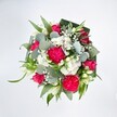 Viewed from above against a pure white background, this exuberant bouquet feels like a bright splash of colour on a calm Nine Elms morning. Hot pink carnations, tightly ruffled and full of movement, form a lively core alongside rich fuchsia roses, some fully open to show their spiralled hearts while others rest in plump bud, promising more blooms to come. Between these bolder flowers, clusters of tiny white spray chrysanthemums and daisy-like blossoms gather like soft clouds, their many petite petals adding a gentle, cushiony texture. Fine sprigs of white gypsophila weave in and out of the design, creating a misty halo that lightens the entire arrangement. A few elongated white buds, reminiscent of alstroemeria or lily blooms just beginning to unfold, lend a quiet elegance and hint at delicate fragrance. The bouquet is anchored by a lush collar of foliage: broad, darker green leaves are folded and curved to frame the flowers, while bright green blades and stems stretch outward, giving a sense of energy and freshness. Rounded, silvery eucalyptus leaves, with their slightly waxy, cool-toned surfaces, add a contemporary London touch that suits the riverside feel of Nine Elms. Soft, even lighting enhances every texture and hue, making the pinks appear vivid, the whites crisp, and the greens deeply refreshing. The overall mood is joyful and affectionate, like a floral embrace perfect for sending congratulations, celebrating a birthday, or lifting someone's spirits at home or in an office overlooking the Thames. It is the sort of carefully balanced hand-tied design you might have delivered the same day to new apartments and townhouses around Battersea Power Station or the surrounding Nine Elms developments, carrying with it a sense of thoughtful celebration and everyday beauty.